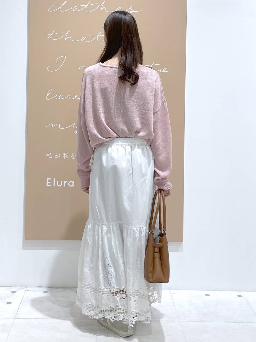 イエロー系のハンドバッグ、ピンク系のニット/セーター、ホワイト系のスカートを着用したレディースの春コーディネートの3枚目の写真