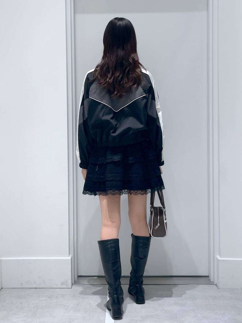 ブラック系のブルゾン、ブラック系のスカート、ブラウン系のボストンバッグを着用したレディースの春コーディネートの3枚目の写真