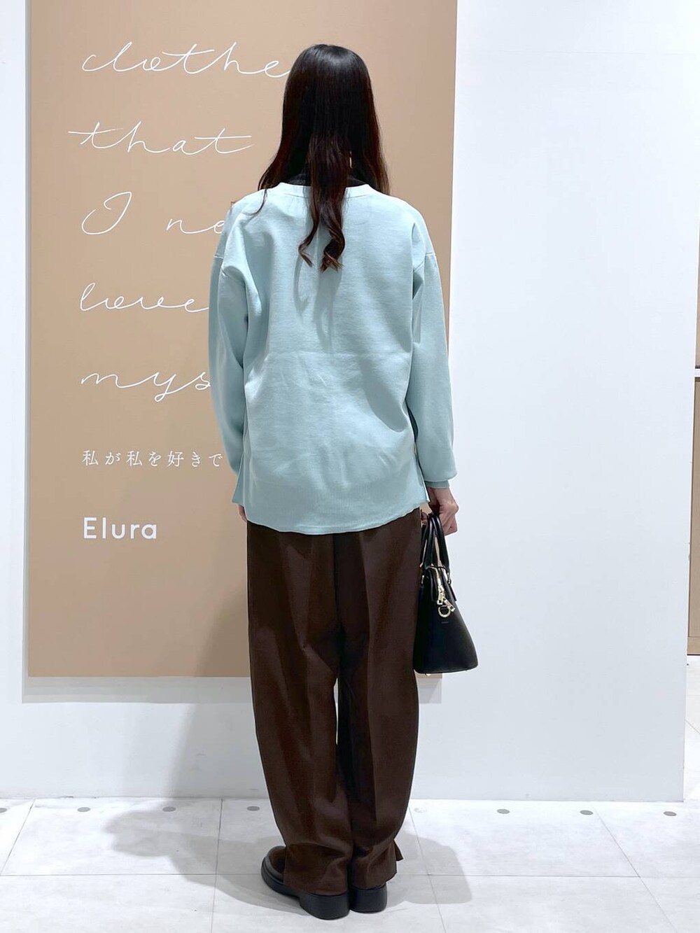 ブラック系のTシャツ/カットソー、グリーン系のカーディガン/ボレロ、ブラック系のハンドバッグを着用したレディースの冬コーディネートの3枚目の写真