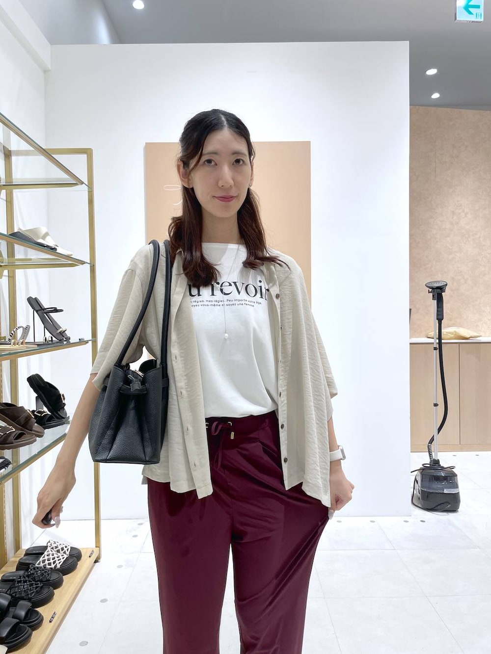ブラック系のハンドバッグ、ブラック系のサンダル、ホワイト系のTシャツ/カットソーを着用したレディースの夏コーディネートの3枚目の写真