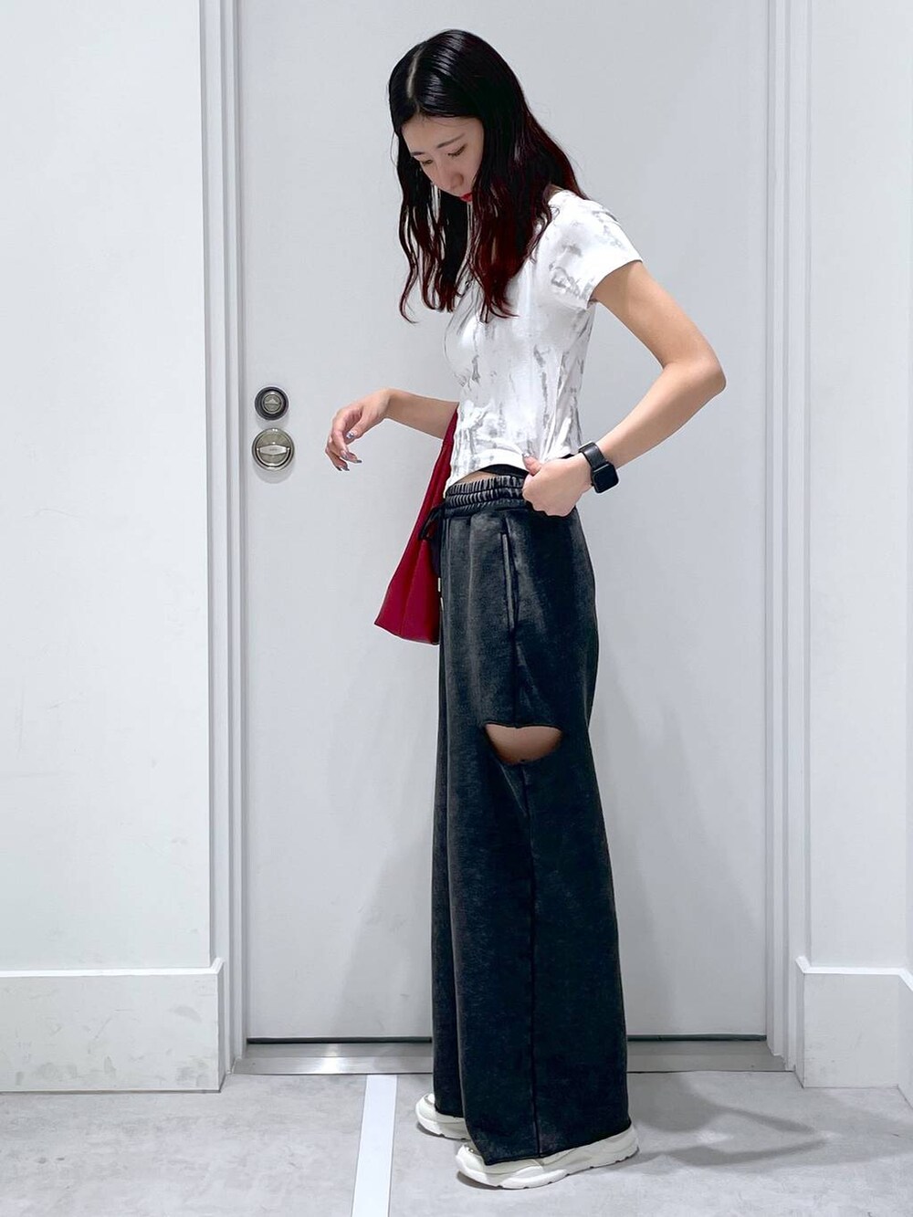 ブラック系のスウェットパンツ、レッド系のショルダーバッグ、ホワイト系のTシャツ/カットソーを着用したレディースの夏コーディネートの2枚目の写真