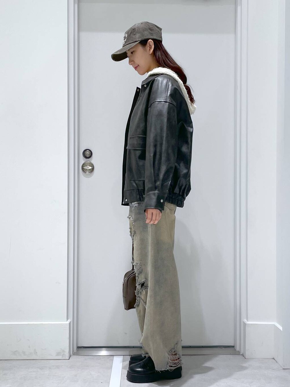 ブルー系のデニムパンツ、ブラウン系のショルダーバッグ、ホワイト系のカーディガン/ボレロを着用したレディースの冬コーディネートの2枚目の写真