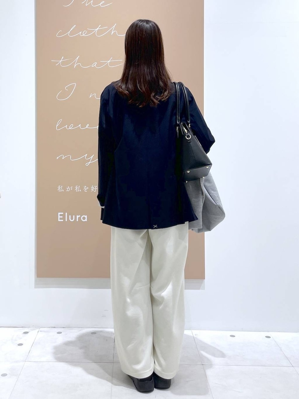 グレー系のパーカー、ブラック系のハンドバッグ、ブルー系のテーラードジャケットを着用したレディースの春コーディネートの3枚目の写真