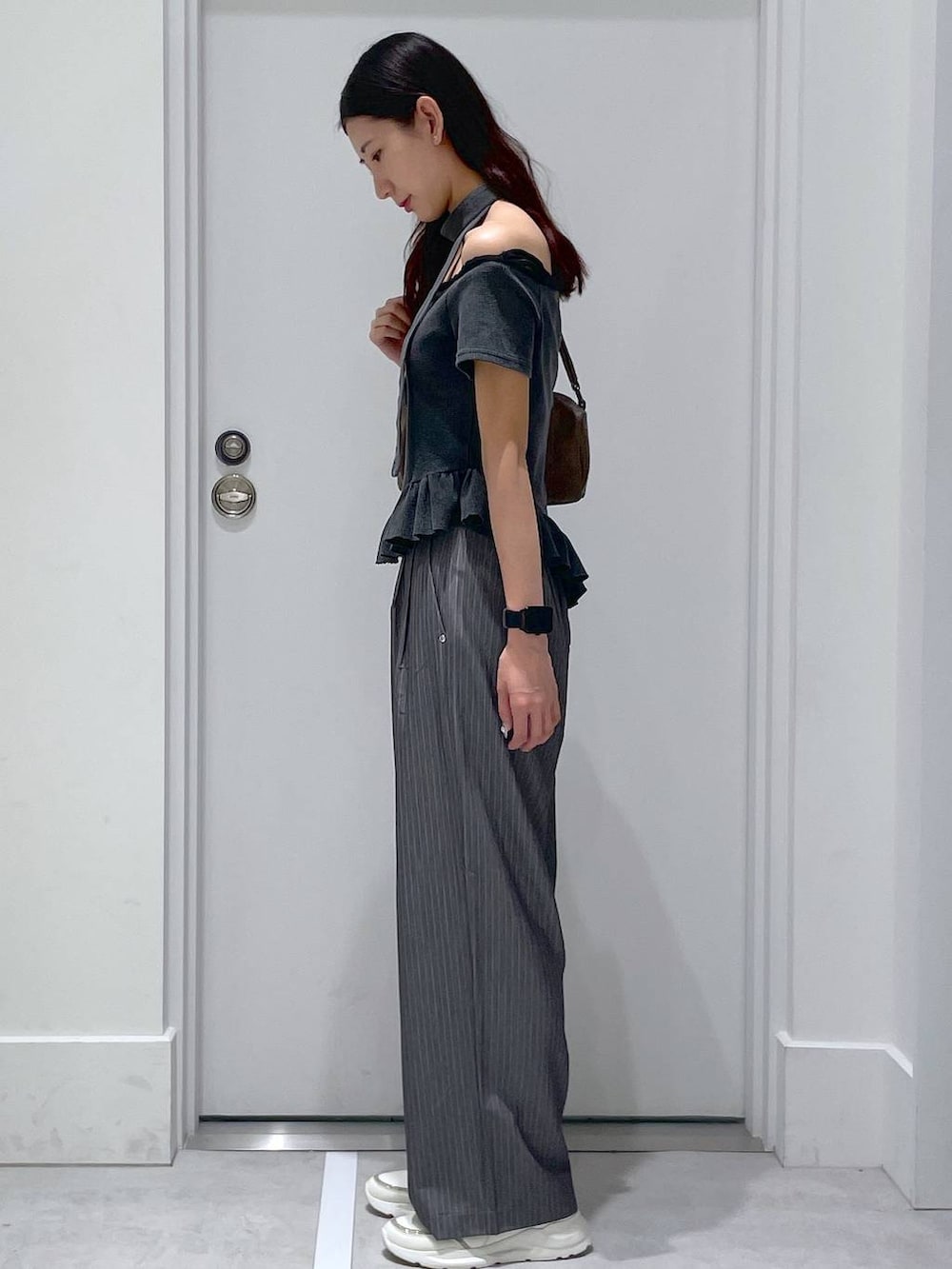 グレー系のスラックス、ブラウン系のハンドバッグ、ブラック系のTシャツ/カットソーを着用したレディースの夏コーディネートの2枚目の写真