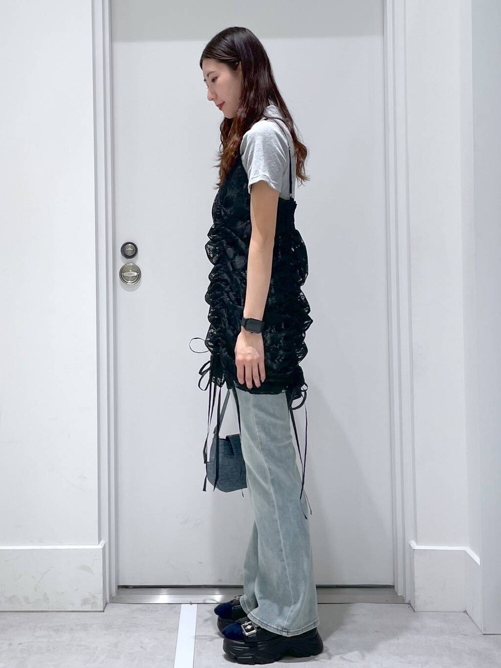 ブルー系のデニムパンツ、ブルー系のショルダーバッグ、ブラック系のワンピースを着用したレディースの春コーディネートの2枚目の写真