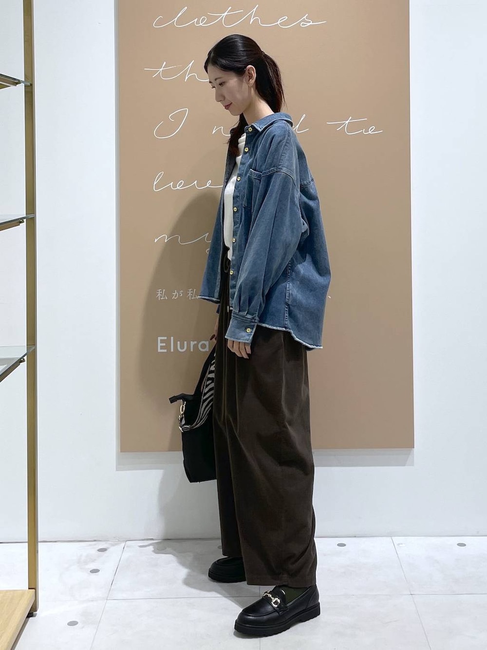 グレー系のその他パンツ、ホワイト系のニット/セーター、ブラック系のショルダーバッグを着用したレディースの秋コーディネートの2枚目の写真