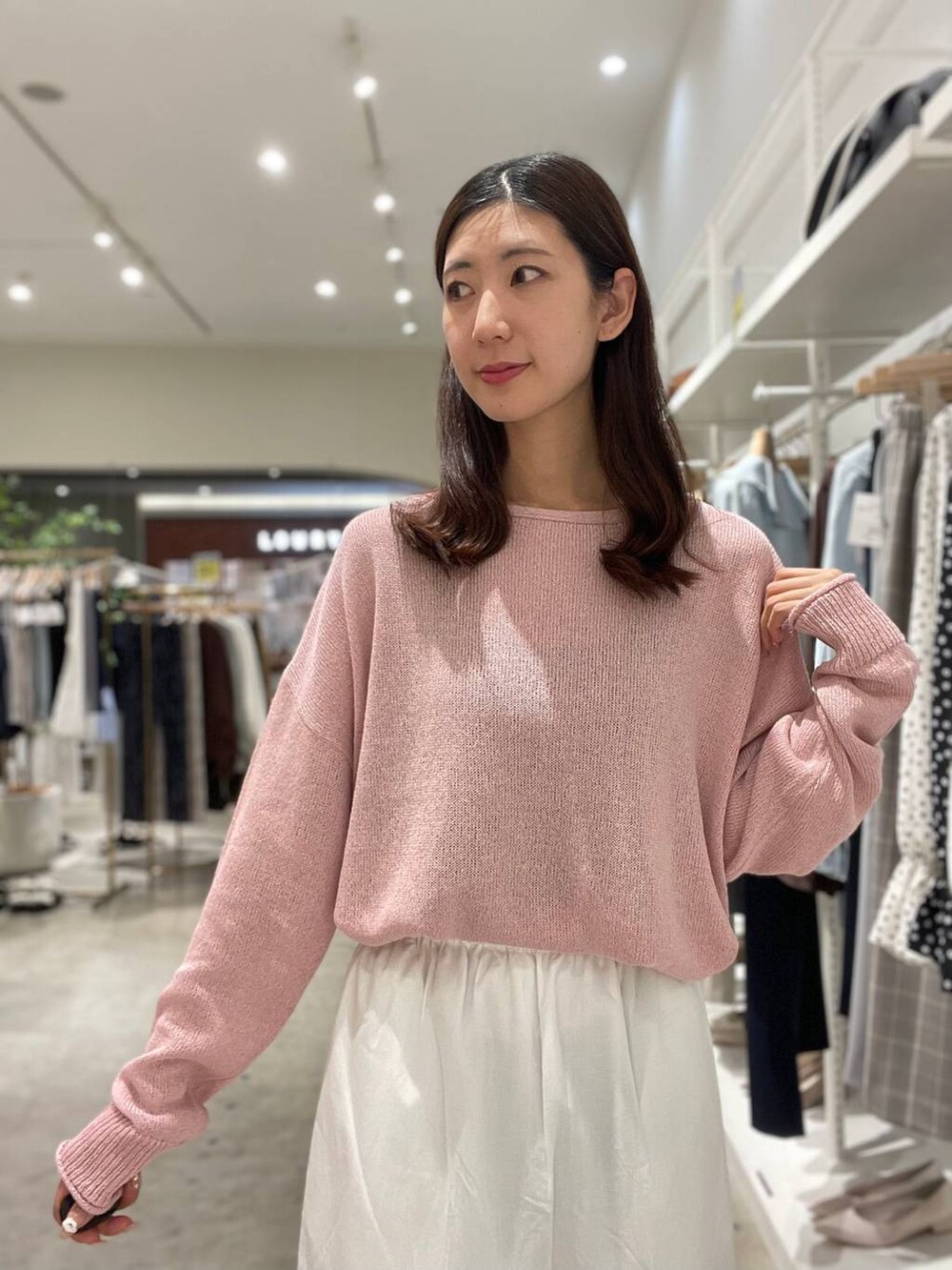 イエロー系のハンドバッグ、ピンク系のニット/セーター、ホワイト系のスカートを着用したレディースの春コーディネートの6枚目の写真