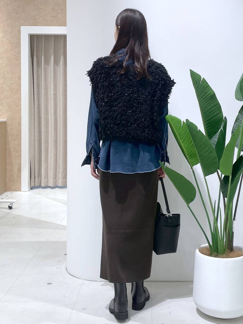 ブラウン系のスカート、ブラック系のブーツ、ブラック系のショルダーバッグを着用したレディースの秋コーディネートの3枚目の写真