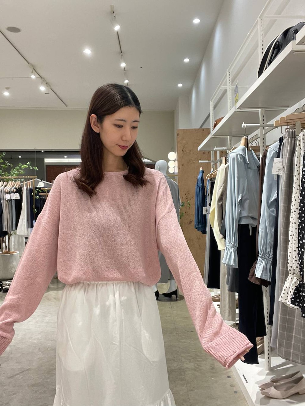 イエロー系のハンドバッグ、ピンク系のニット/セーター、ホワイト系のスカートを着用したレディースの春コーディネートの4枚目の写真