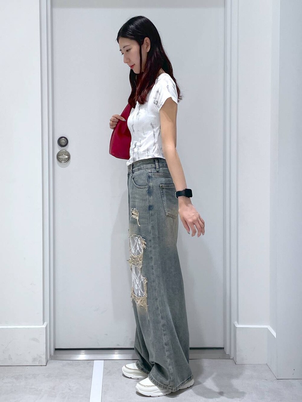 ブルー系のデニムパンツ、レッド系のショルダーバッグ、ホワイト系のTシャツ/カットソーを着用したレディースの夏コーディネートの2枚目の写真