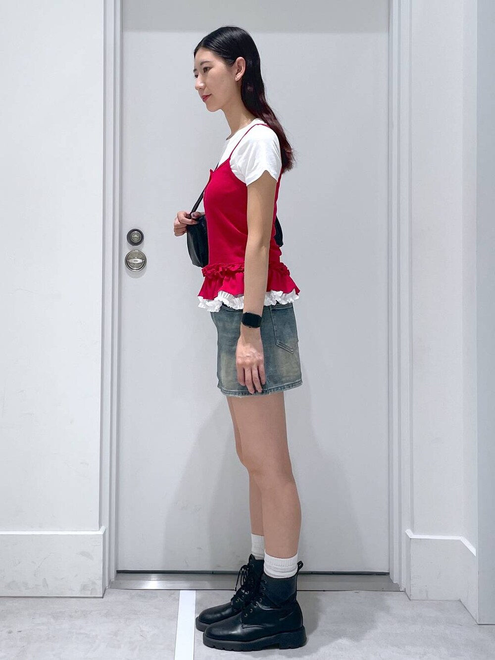 ブルー系のデニムスカート、ブラック系のハンドバッグ、ホワイト系のTシャツ/カットソーを着用したレディースの夏コーディネートの2枚目の写真
