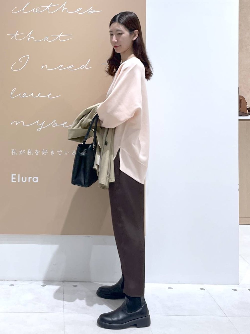 ブラウン系のスカート、ブラック系のハンドバッグ、ピンク系のニット/セーターを着用したレディースの春コーディネートの2枚目の写真