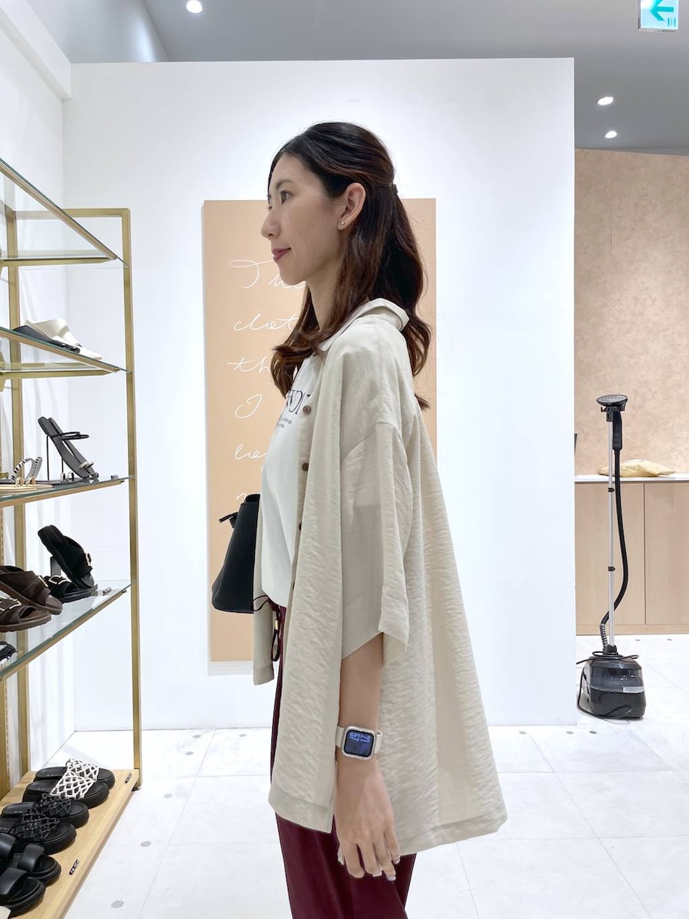 ブラック系のハンドバッグ、ブラック系のサンダル、ホワイト系のTシャツ/カットソーを着用したレディースの夏コーディネートの2枚目の写真