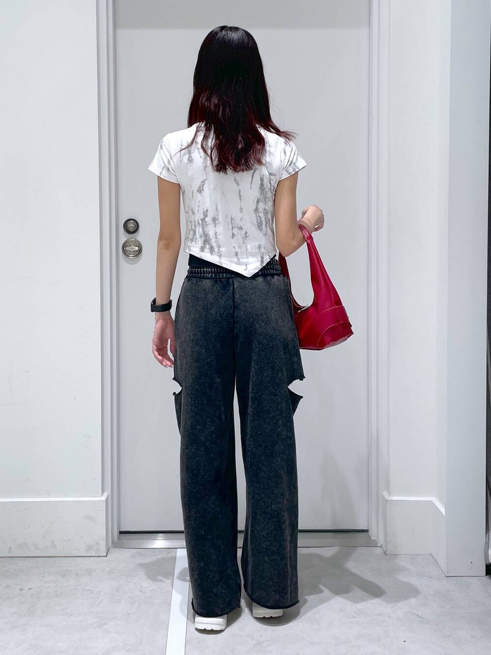 ブラック系のスウェットパンツ、レッド系のショルダーバッグ、ホワイト系のTシャツ/カットソーを着用したレディースの夏コーディネートの3枚目の写真