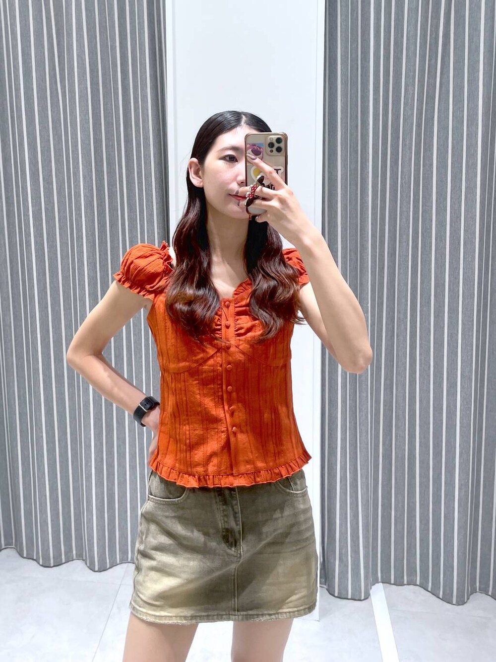 ブラック系のブーツ、オレンジ系のシャツ/ブラウス、ブラウン系のデニムスカートを着用したレディースの夏コーディネートの2枚目の写真