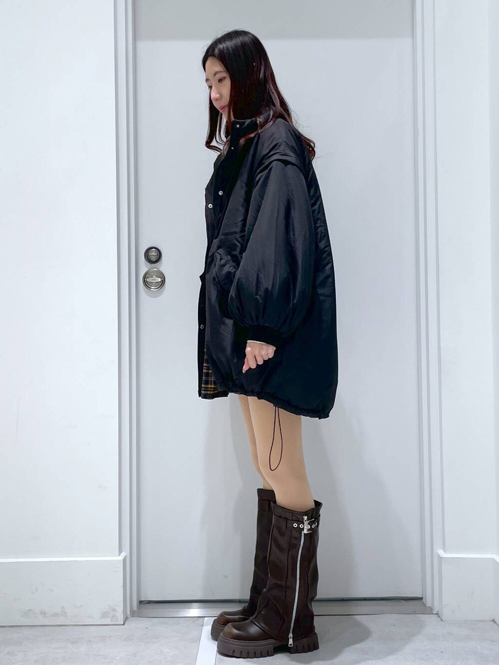 ブラック系のブルゾン、ブラウン系のブーツ、イエロー系のその他パンツを着用したレディースの冬コーディネートの2枚目の写真