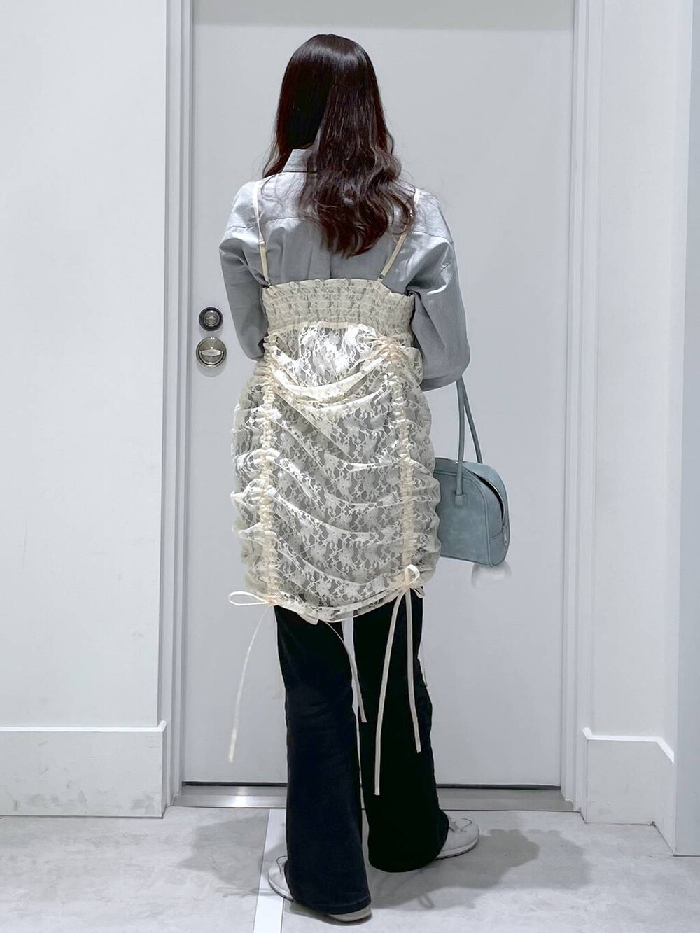 ベージュ系のワンピース、ブルー系のデニムパンツ、ブルー系のショルダーバッグを着用したレディースの春コーディネートの3枚目の写真