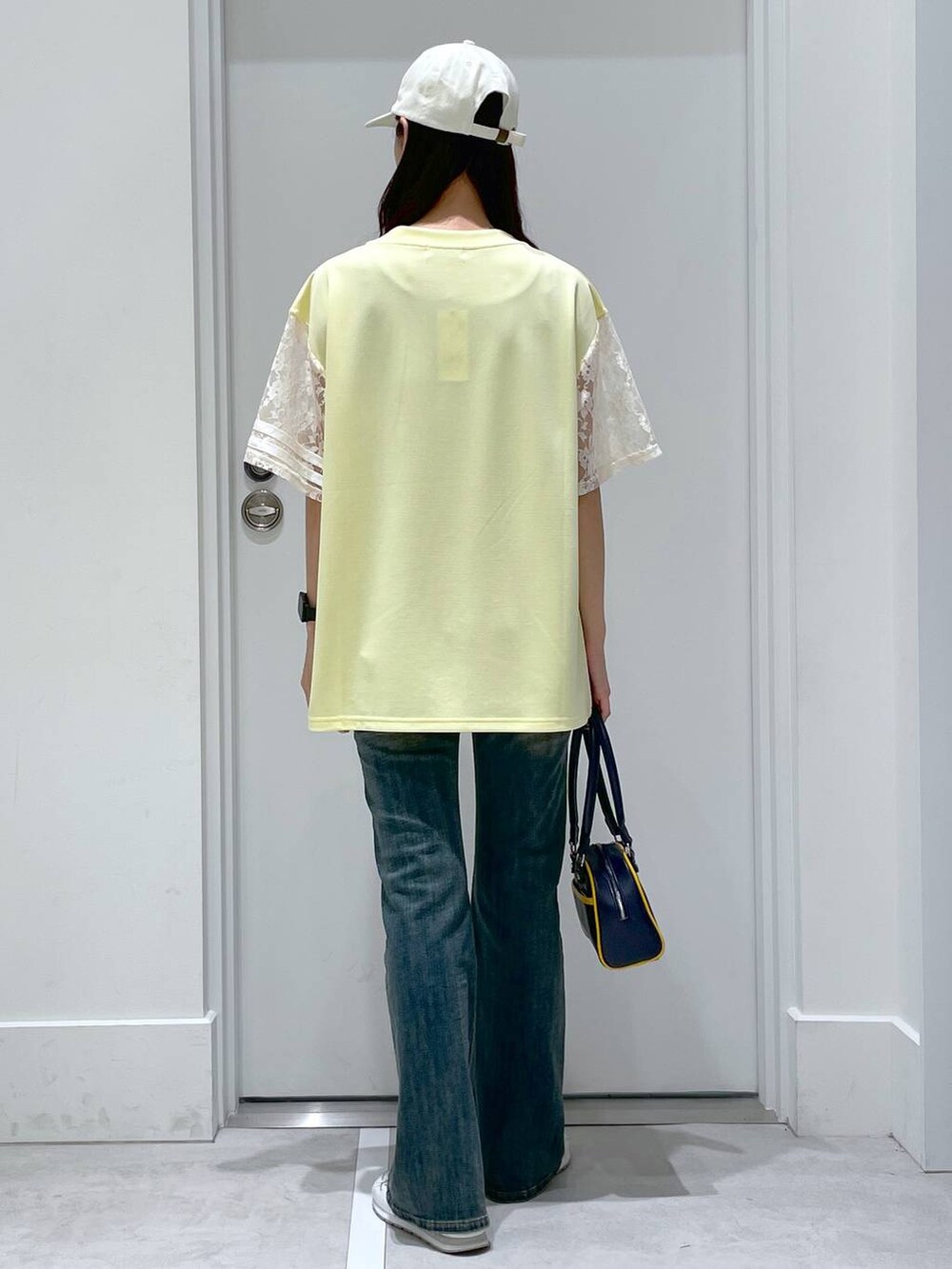 ブルー系のデニムパンツ、ブルー系のボストンバッグ、イエロー系のTシャツ/カットソーを着用したレディースの春コーディネートの3枚目の写真