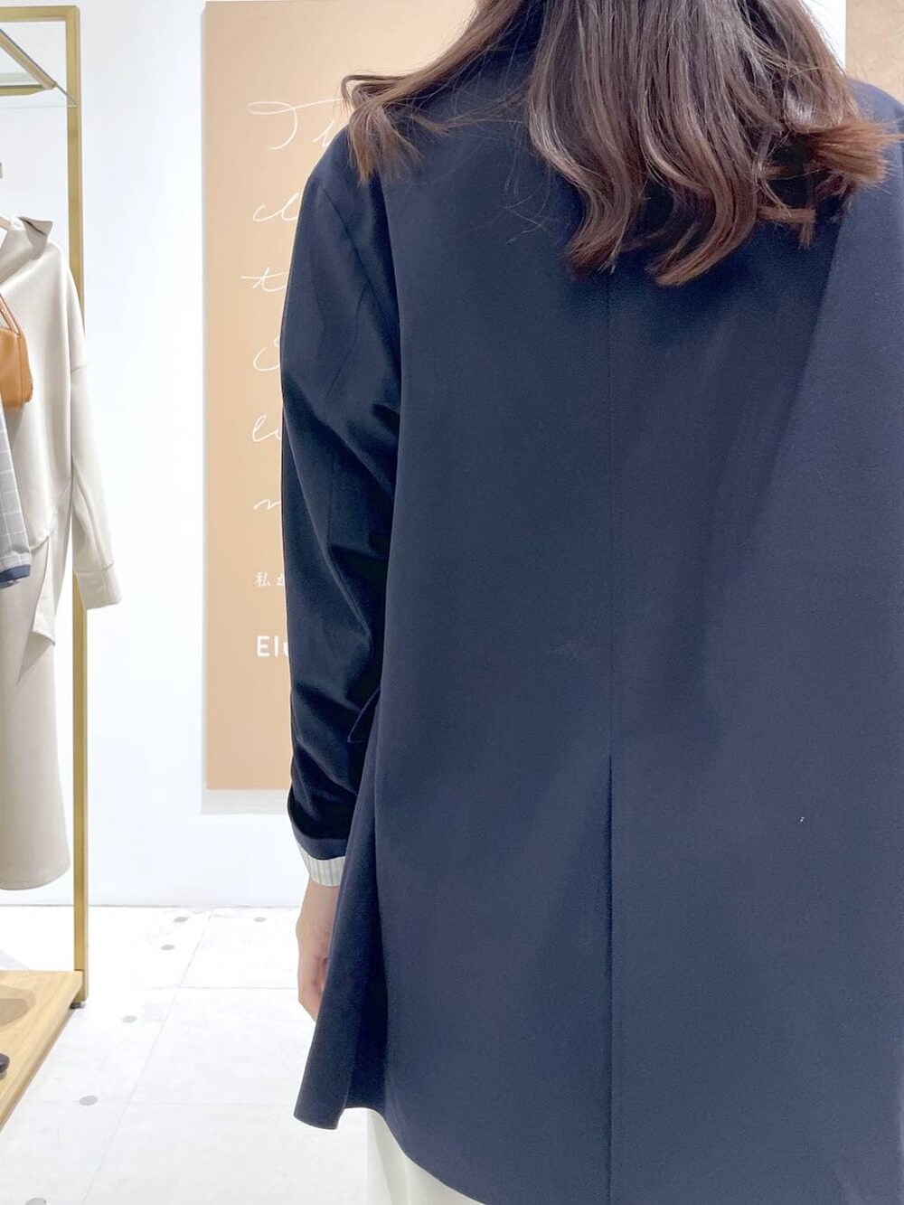 グレー系のパーカー、ブラック系のハンドバッグ、ブルー系のテーラードジャケットを着用したレディースの春コーディネートの6枚目の写真