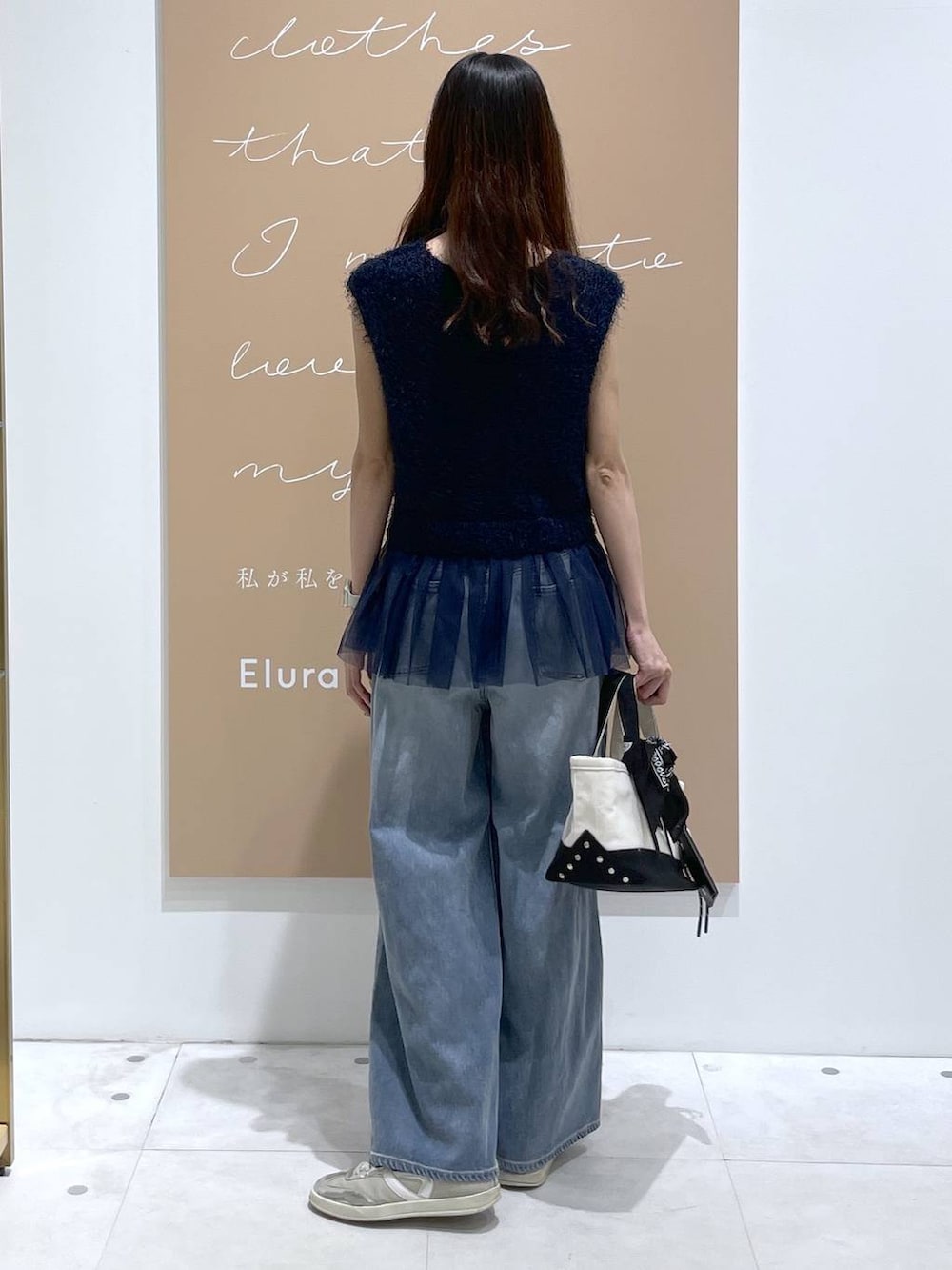 ブルー系のニット/セーター、ブラック系のトートバッグ、ブルー系のデニムパンツを着用したレディースの夏コーディネートの3枚目の写真