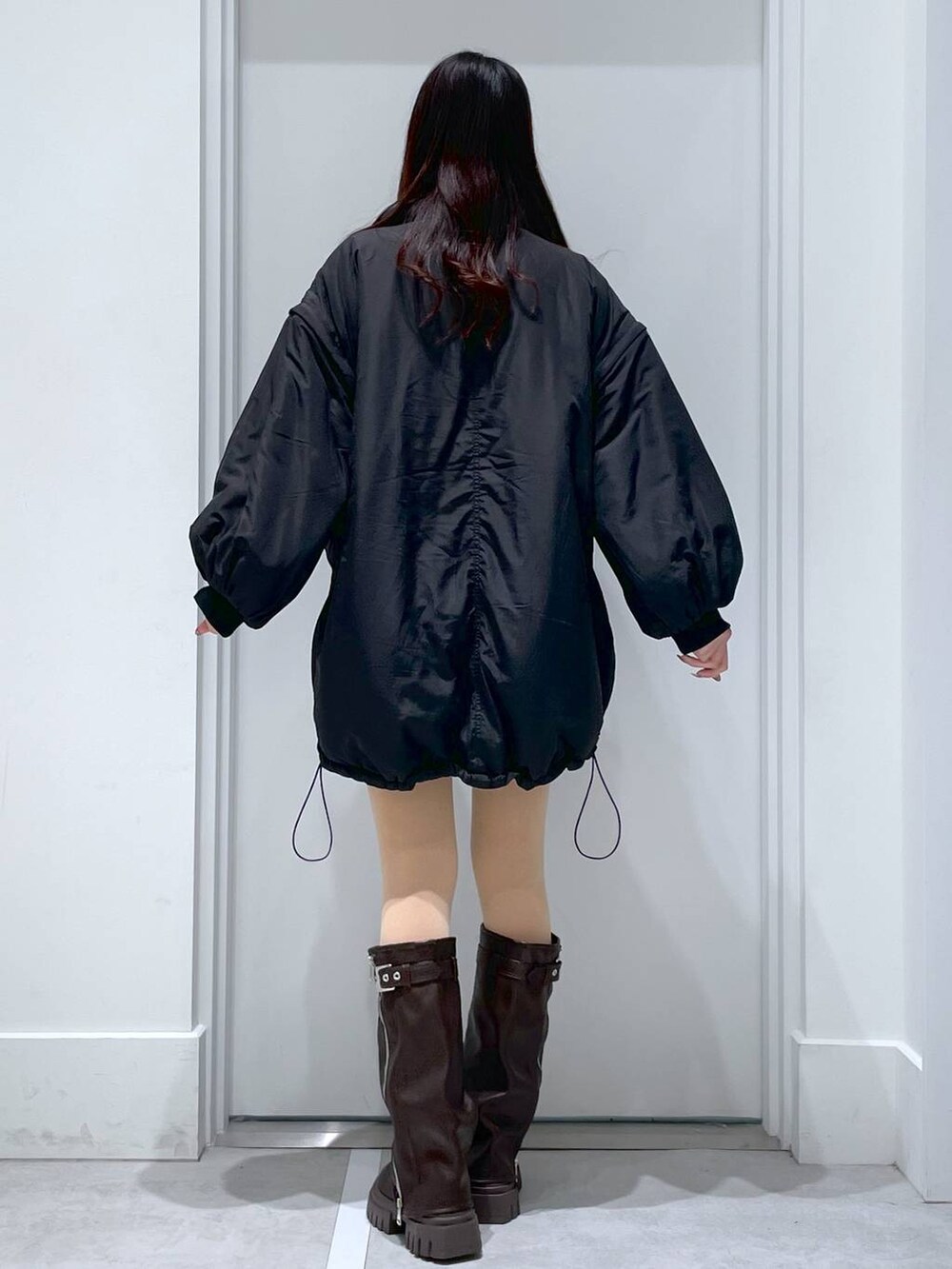 ブラック系のブルゾン、ブラウン系のブーツ、イエロー系のその他パンツを着用したレディースの冬コーディネートの3枚目の写真