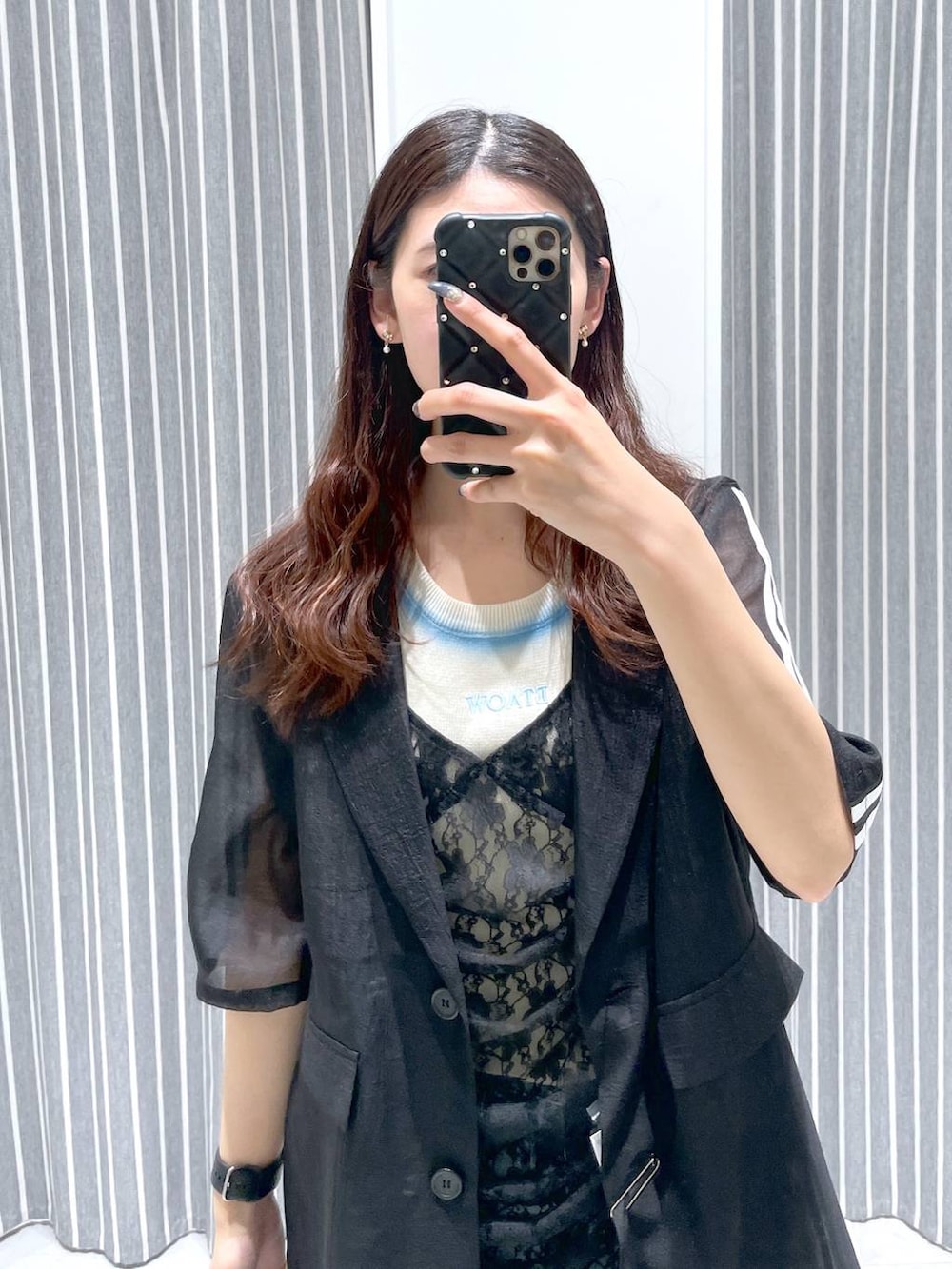 ブルー系のデニムパンツ、ブラック系のワンピース、ブラック系のテーラードジャケットを着用したレディースの春コーディネートの3枚目の写真