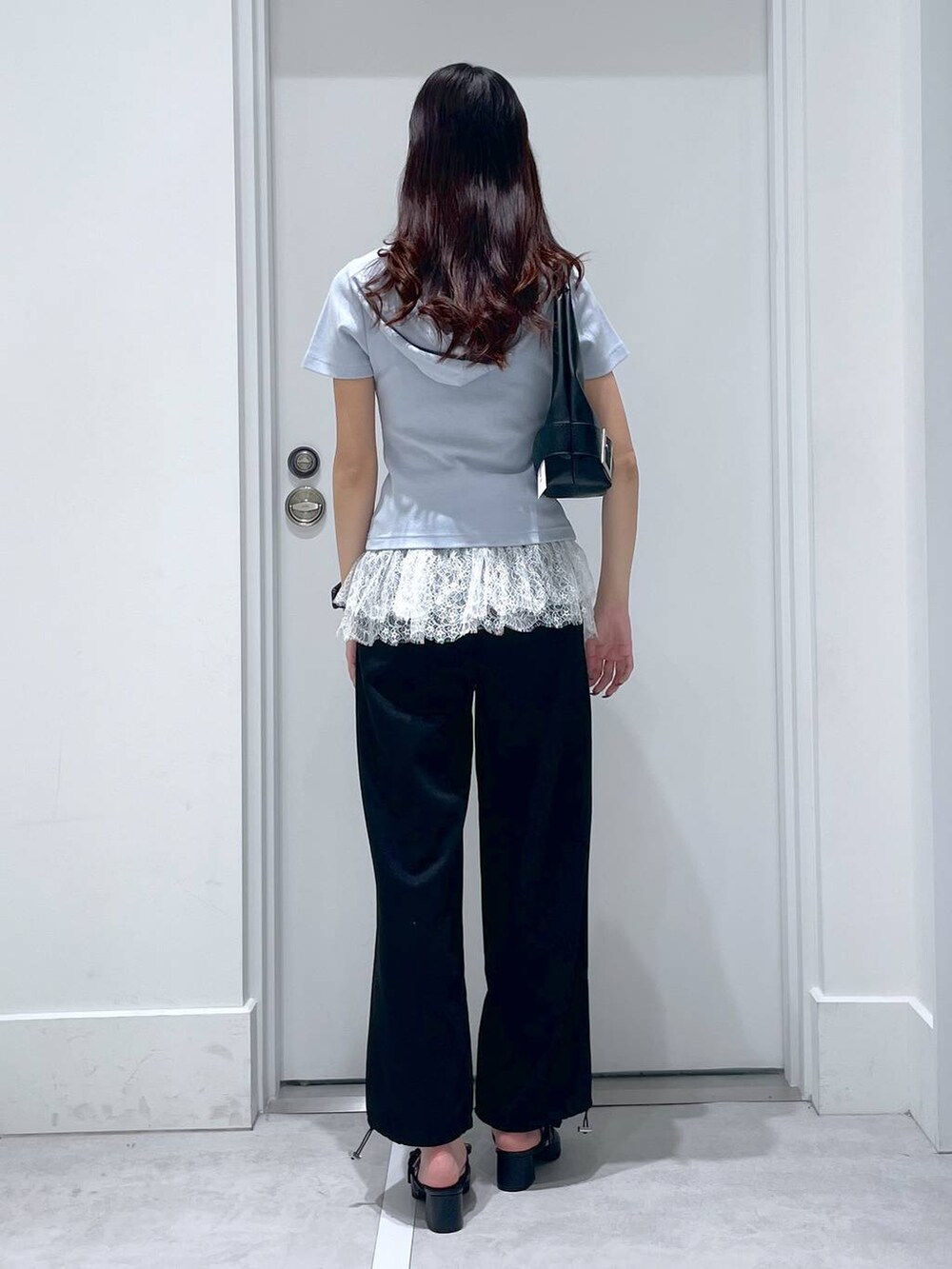 ブラック系のパンプス、ブルー系のパーカー、ブラック系のショルダーバッグを着用したレディースの春コーディネートの3枚目の写真