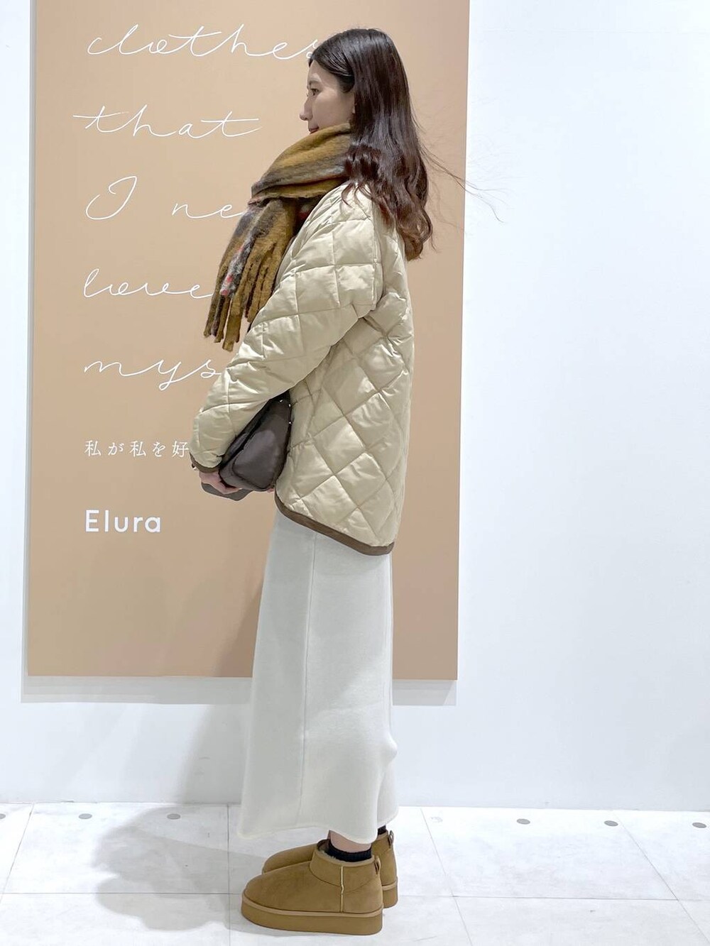 ブラウン系のブーツ、ベージュ系のダウンジャケット/コート、ブラック系のショルダーバッグを着用したレディースの冬コーディネートの2枚目の写真