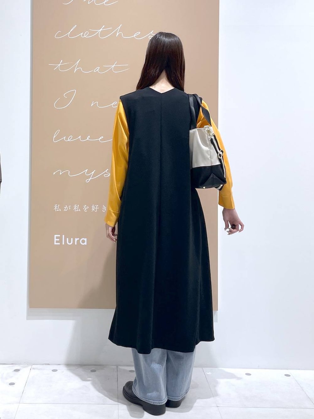 ベージュ系のトートバッグ、ホワイト系のタンクトップ、ブラック系のジャンパースカートを着用したレディースの春コーディネートの3枚目の写真