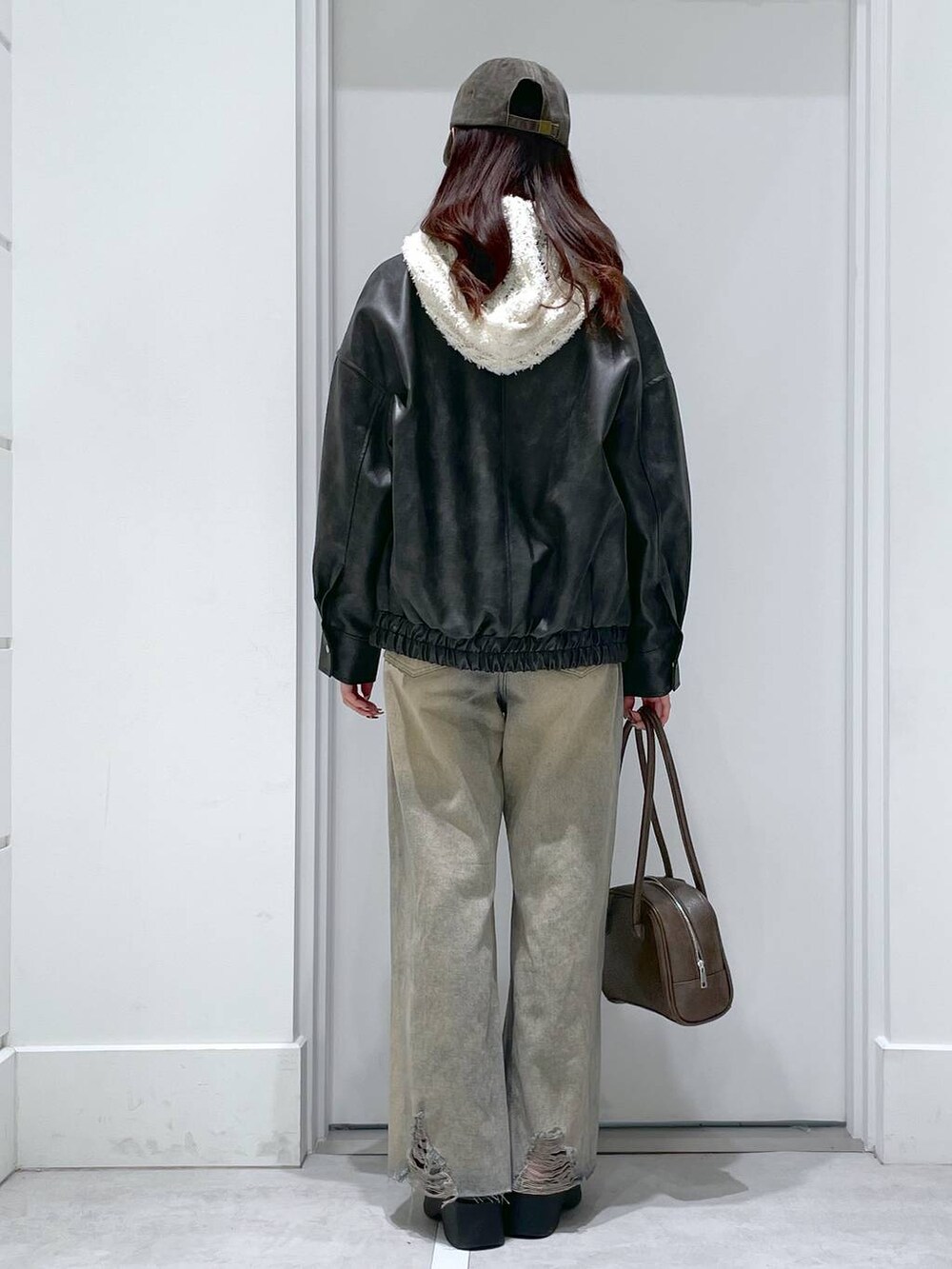 ブルー系のデニムパンツ、ブラウン系のショルダーバッグ、ホワイト系のカーディガン/ボレロを着用したレディースの冬コーディネートの3枚目の写真