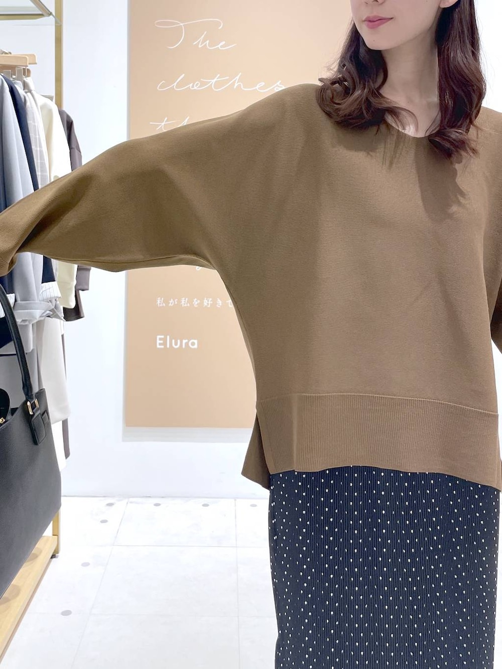 ブラック系のスカート、ブラック系のハンドバッグ、ブラウン系のニット/セーターを着用したレディースの春コーディネートの5枚目の写真