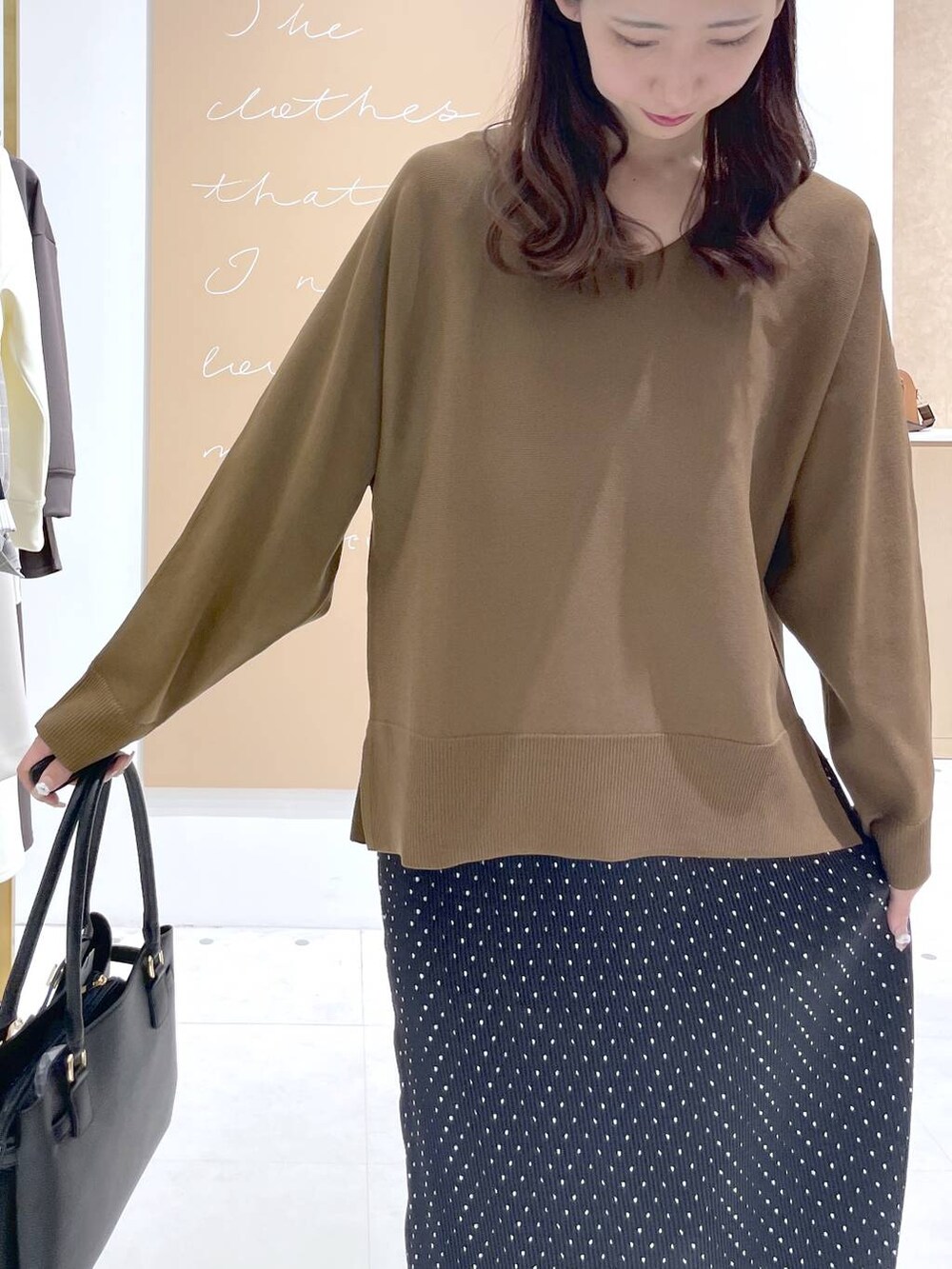 ブラック系のスカート、ブラック系のハンドバッグ、ブラウン系のニット/セーターを着用したレディースの春コーディネートの4枚目の写真