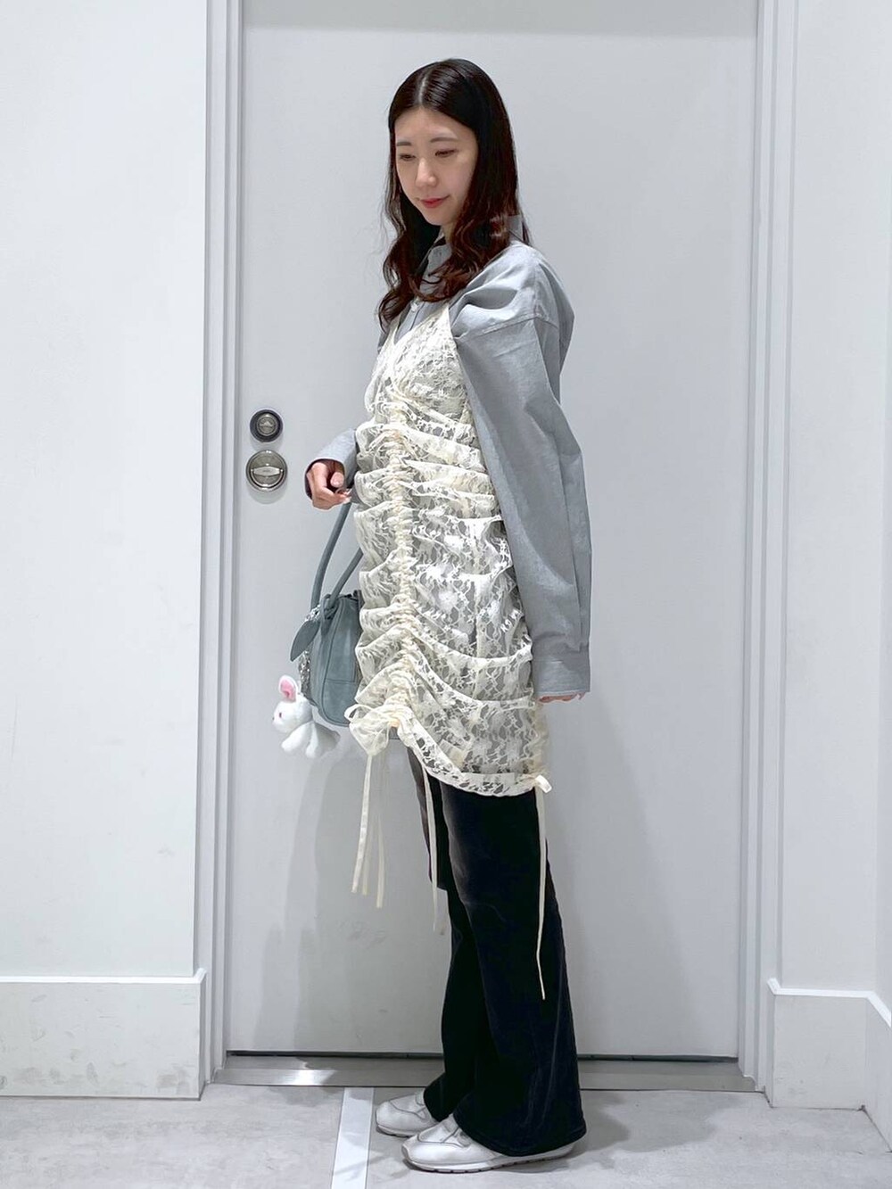 ベージュ系のワンピース、ブルー系のデニムパンツ、ブルー系のショルダーバッグを着用したレディースの春コーディネートの2枚目の写真