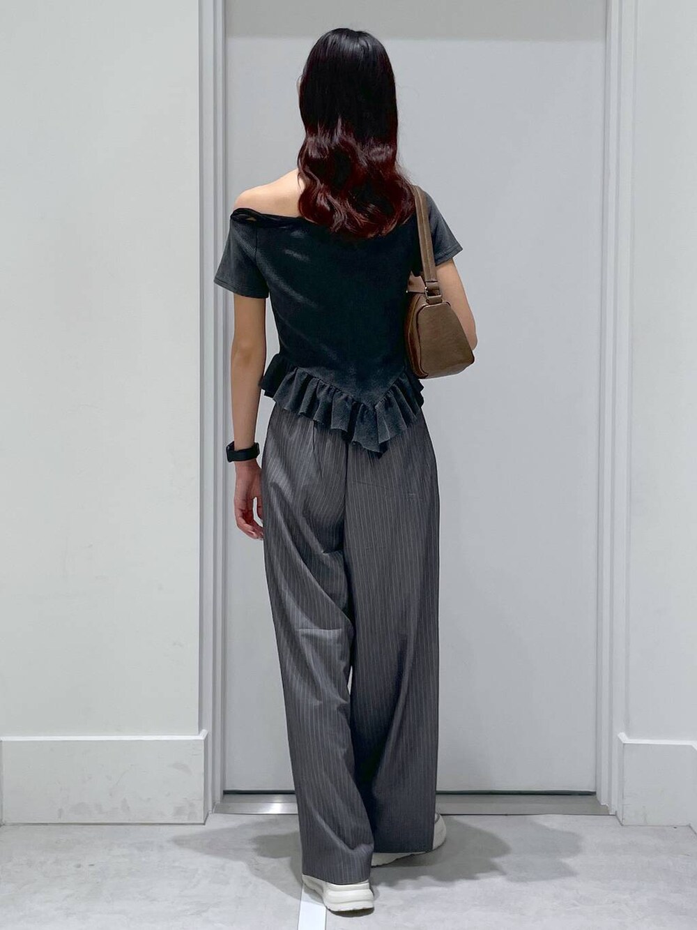 グレー系のスラックス、ブラウン系のハンドバッグ、ブラック系のTシャツ/カットソーを着用したレディースの夏コーディネートの3枚目の写真