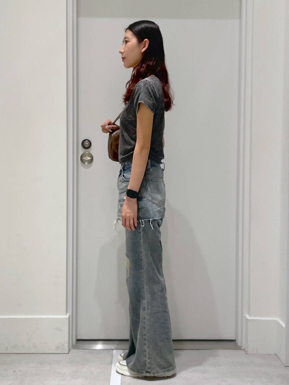 ブラック系のTシャツ/カットソー、ブルー系のデニムパンツ、ブラウン系のハンドバッグを着用したレディースの夏コーディネートの2枚目の写真