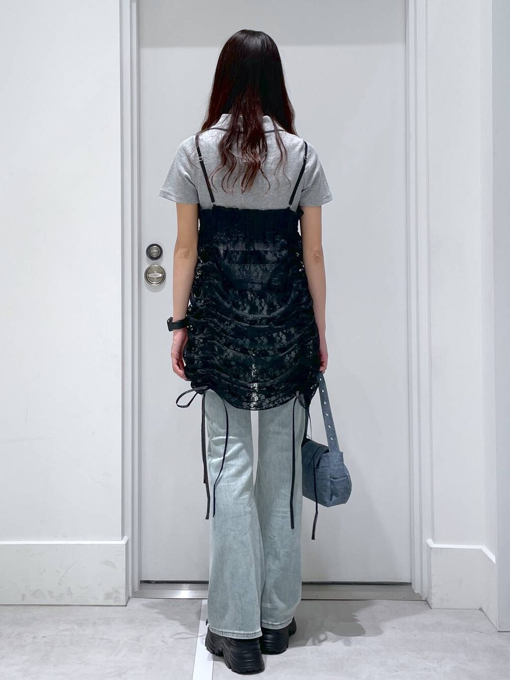 ブルー系のデニムパンツ、ブルー系のショルダーバッグ、ブラック系のワンピースを着用したレディースの春コーディネートの3枚目の写真