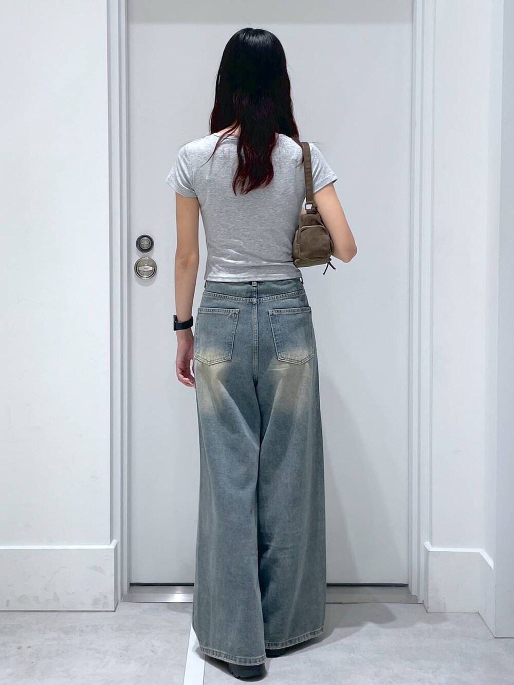 ブルー系のデニムパンツ、グレー系のTシャツ/カットソー、ブラウン系のハンドバッグを着用したレディースの夏コーディネートの3枚目の写真
