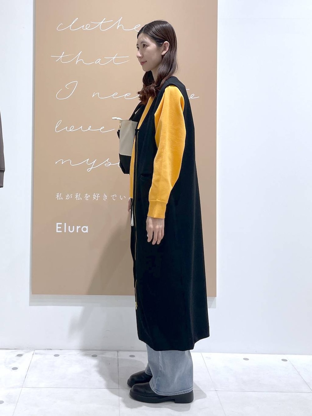 ベージュ系のトートバッグ、ホワイト系のタンクトップ、ブラック系のジャンパースカートを着用したレディースの春コーディネートの2枚目の写真