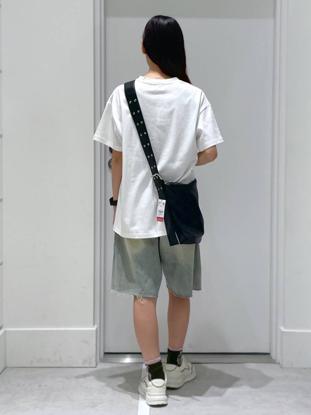 ブルー系のデニムパンツ、ブラック系のショルダーバッグ、ホワイト系のTシャツ/カットソーを着用したレディースの夏コーディネートの3枚目の写真