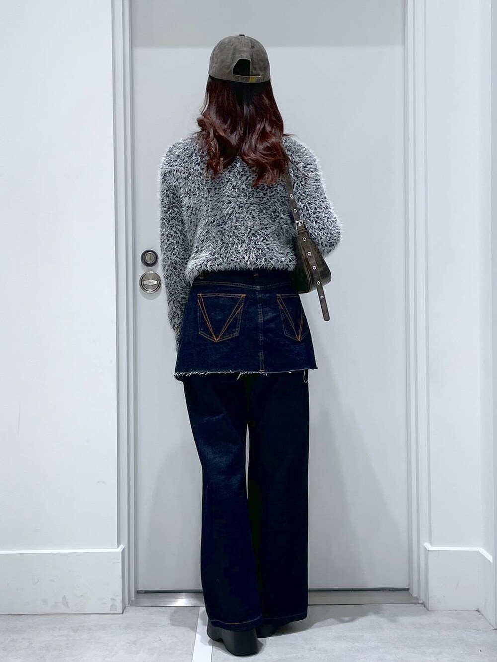 ブラック系のスリッポン、ブルー系のデニムパンツ、ブラック系のニット/セーターを着用したレディースの冬コーディネートの3枚目の写真