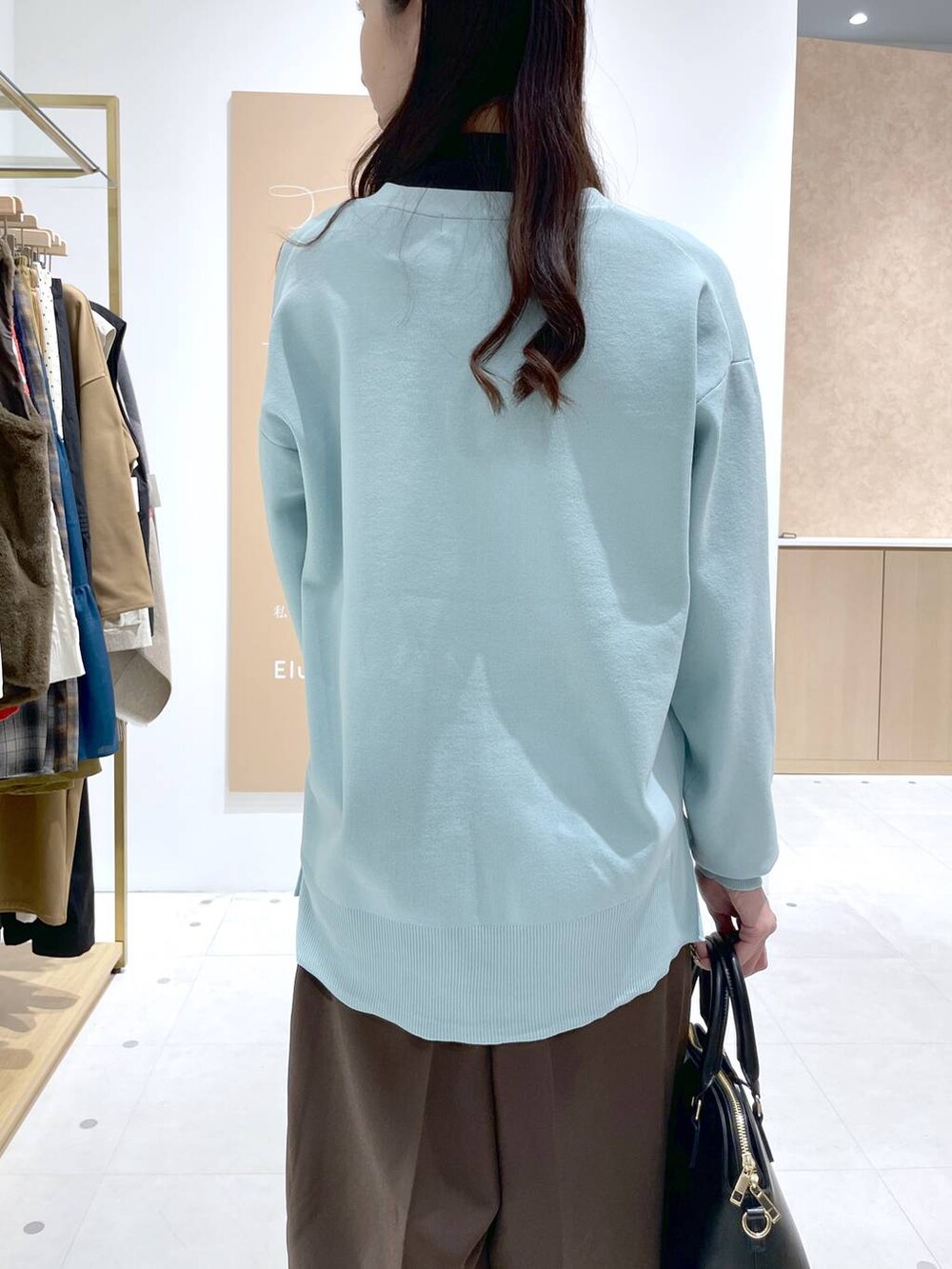 ブラック系のTシャツ/カットソー、グリーン系のカーディガン/ボレロ、ブラック系のハンドバッグを着用したレディースの冬コーディネートの6枚目の写真