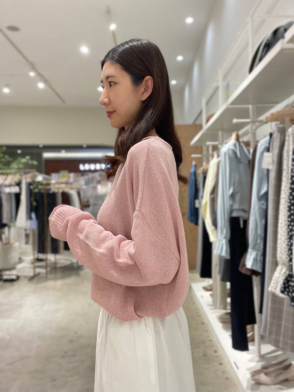 イエロー系のハンドバッグ、ピンク系のニット/セーター、ホワイト系のスカートを着用したレディースの春コーディネートの7枚目の写真