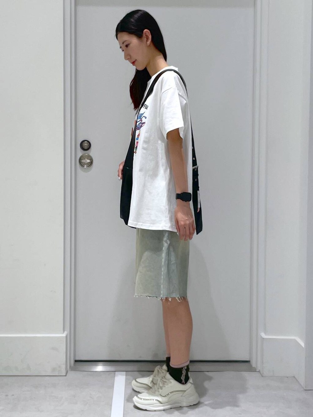 ブルー系のデニムパンツ、ブラック系のショルダーバッグ、ホワイト系のTシャツ/カットソーを着用したレディースの夏コーディネートの2枚目の写真