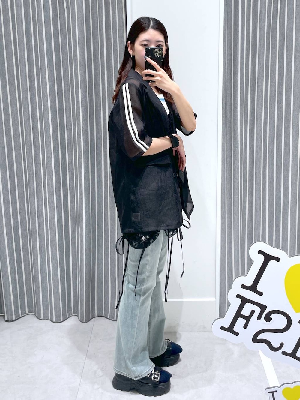 ブルー系のデニムパンツ、ブラック系のワンピース、ブラック系のテーラードジャケットを着用したレディースの春コーディネートの2枚目の写真