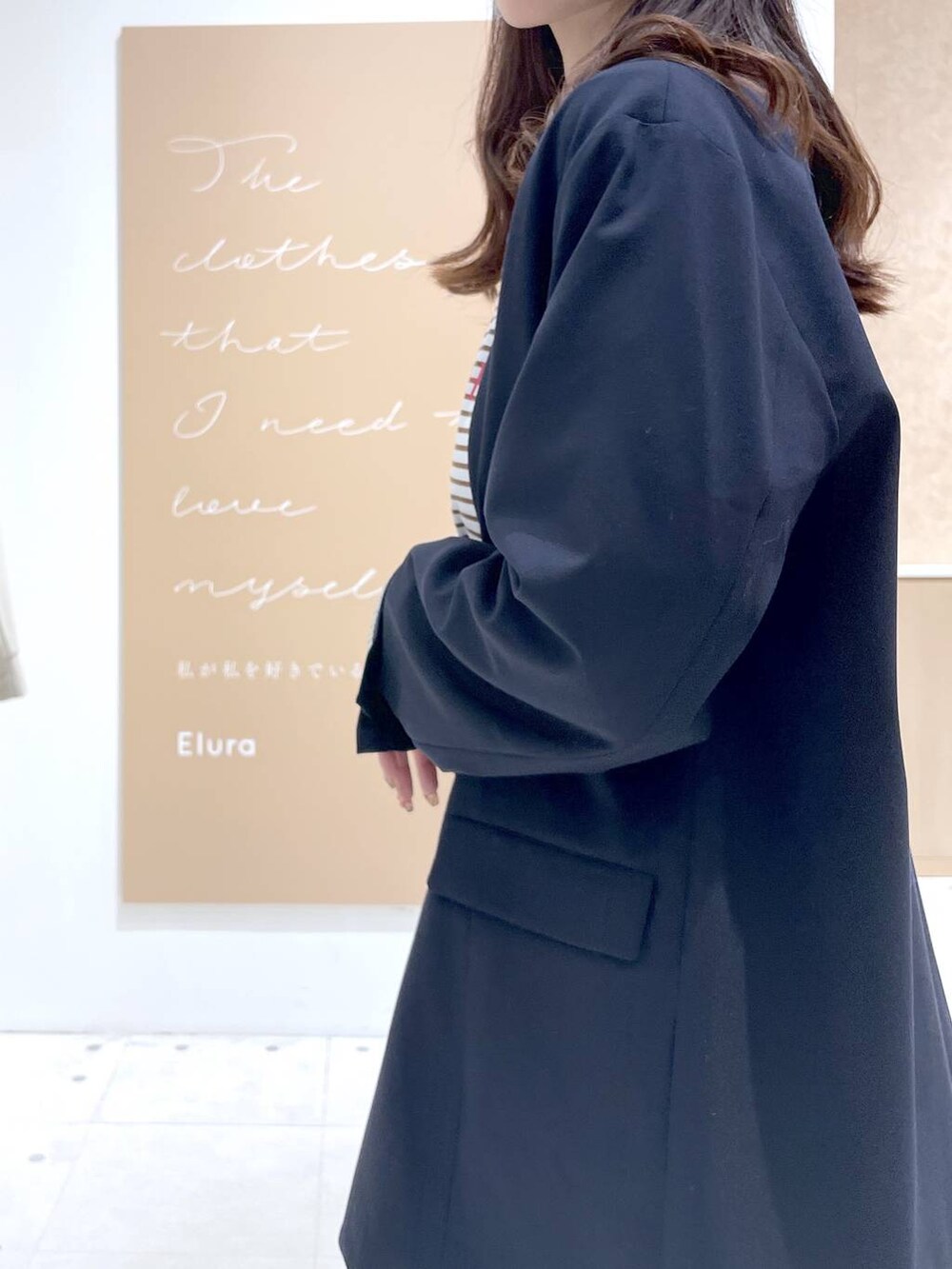 グレー系のパーカー、ブラック系のハンドバッグ、ブルー系のテーラードジャケットを着用したレディースの春コーディネートの5枚目の写真