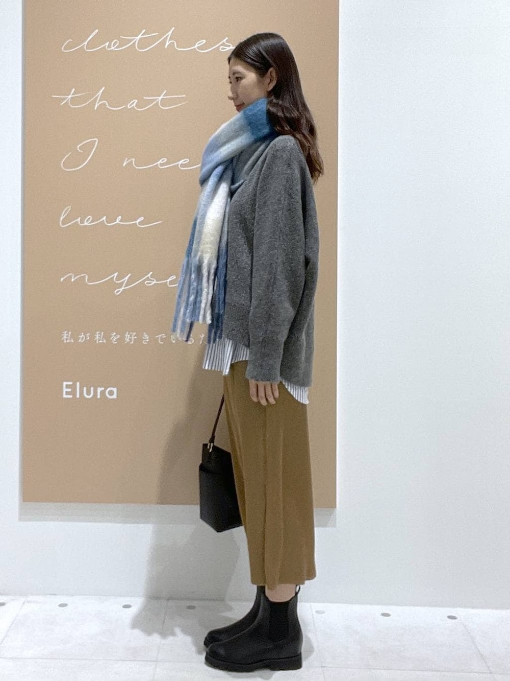 ブラック系のブーツ、ブラック系のショルダーバッグ、グレー系のニット/セーターを着用したレディースの秋コーディネートの2枚目の写真