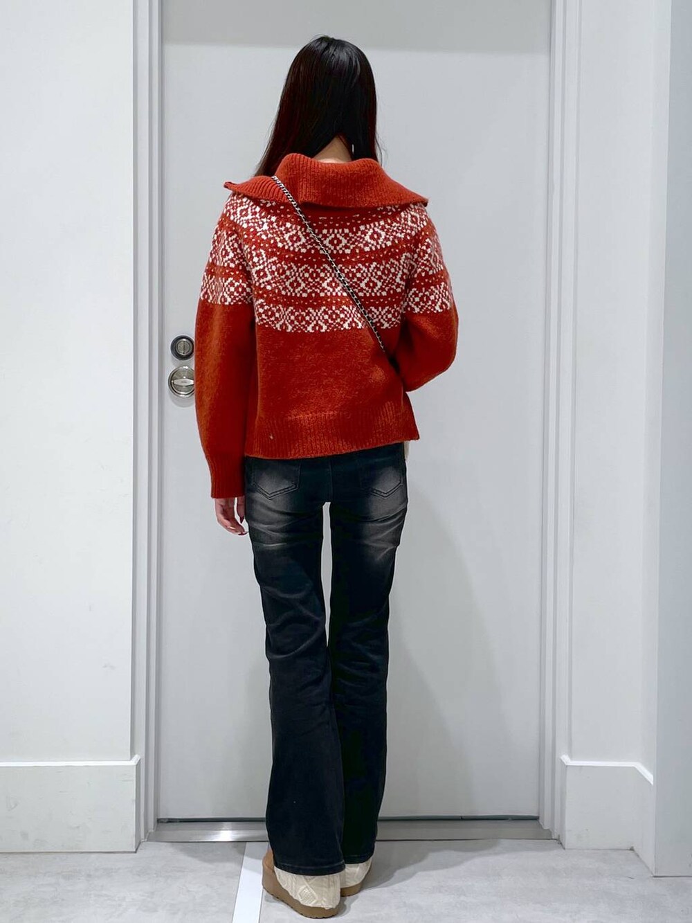 レッド系のニット/セーター、ブラック系のデニムパンツ、ブラック系のショルダーバッグを着用したレディースの冬コーディネートの3枚目の写真