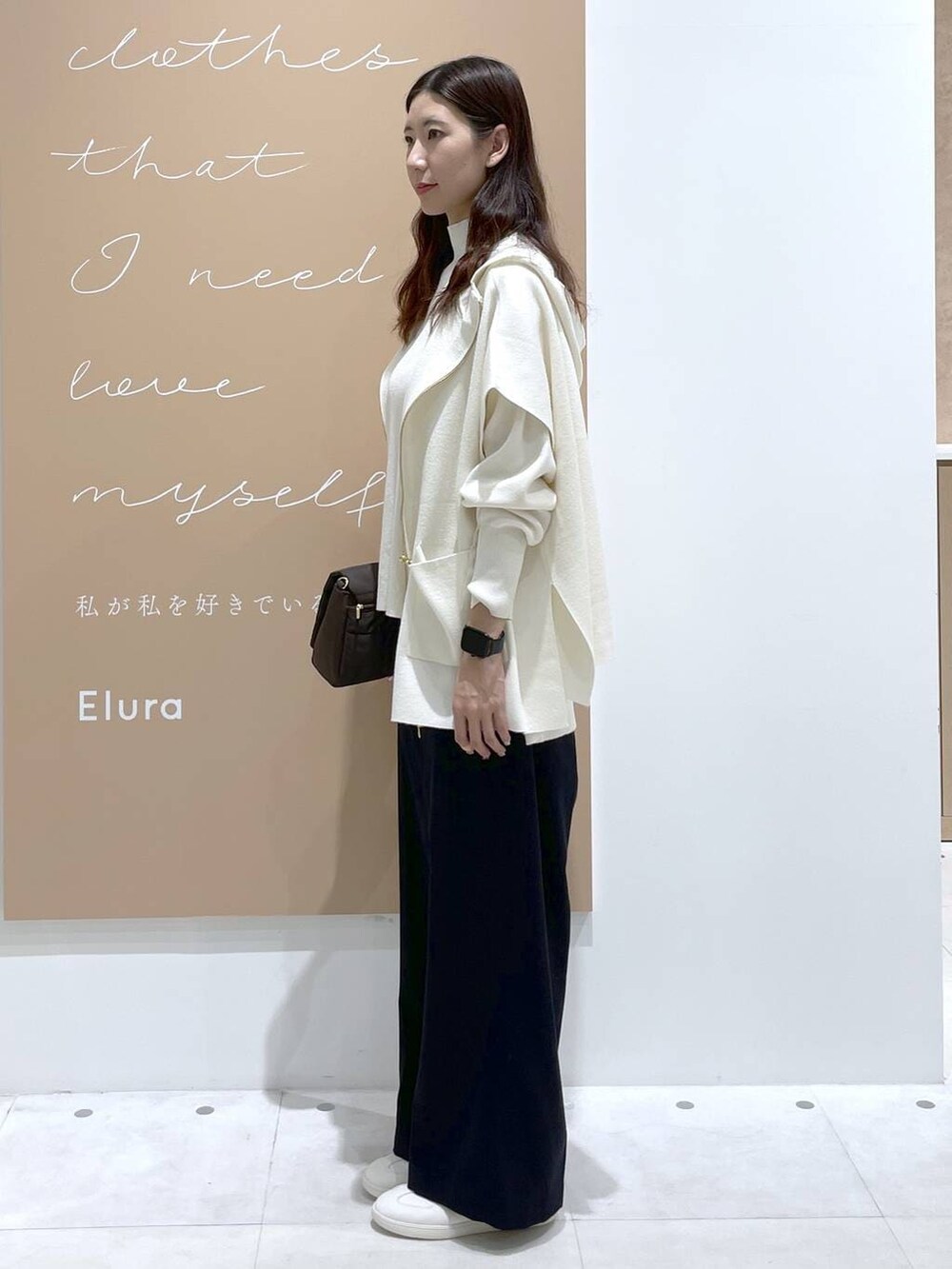 ブラック系のニット/セーター、ホワイト系のベスト、ブラウン系のショルダーバッグを着用したレディースの冬コーディネートの2枚目の写真