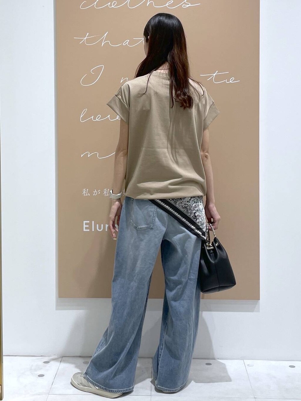 ブラック系のハンドバッグ、ブルー系のデニムパンツ、シルバー系のネックレスを着用したレディースの夏コーディネートの3枚目の写真
