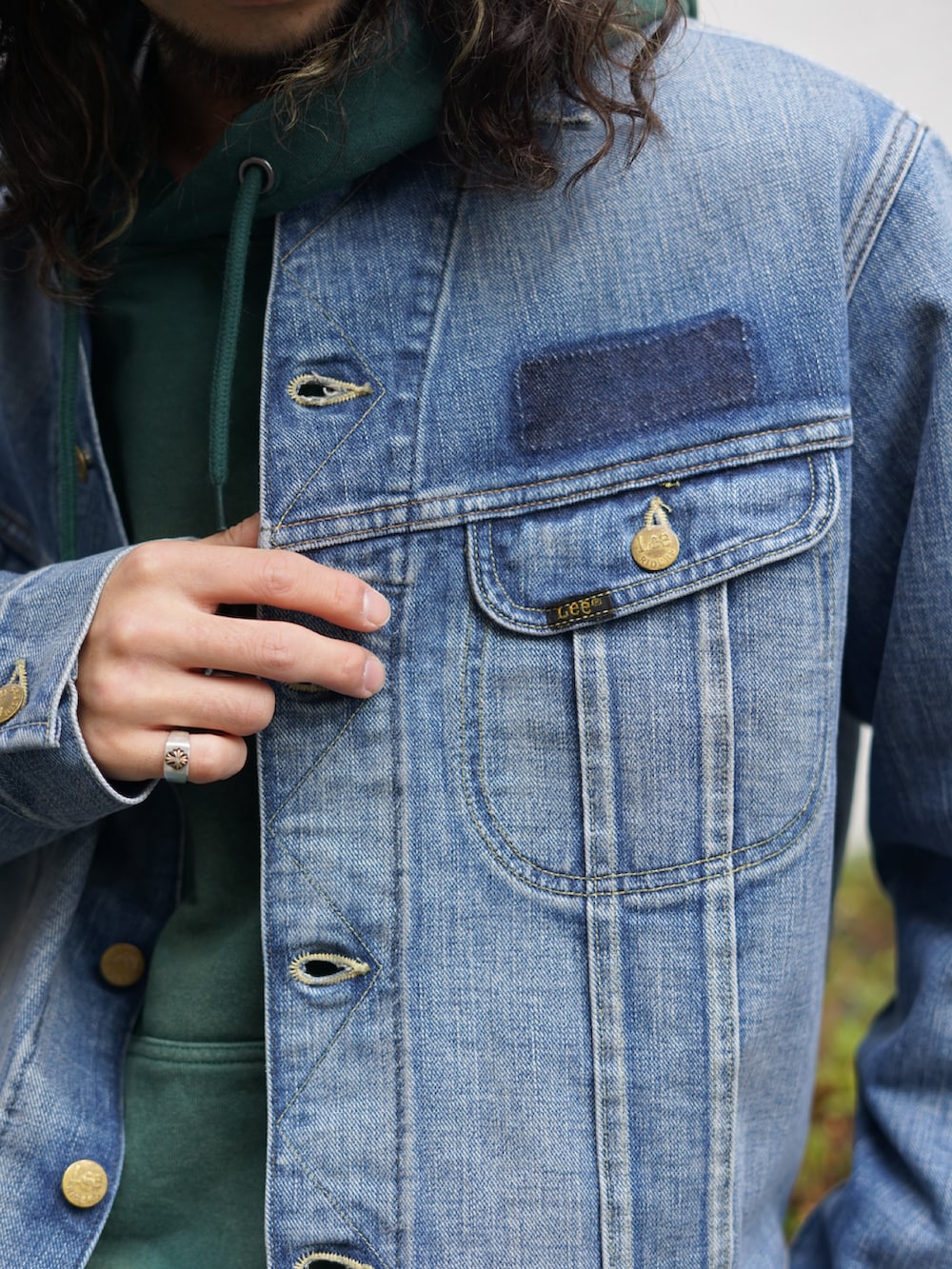 ブルー系のデニムジャケット、グリーン系のパーカー、ブルー系のデニムパンツを着用したメンズの冬コーディネートの3枚目の写真